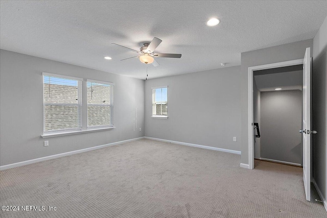 carpeted spare room with ceiling fan and a textured ceiling