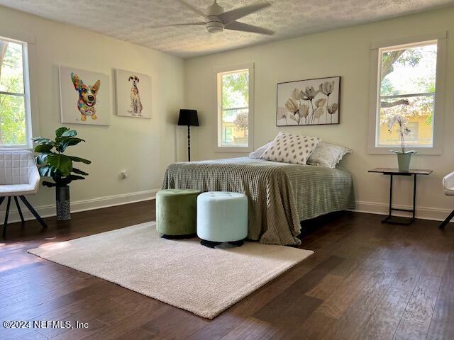 bedroom with a textured ceiling, dark hardwood / wood-style floors, and ceiling fan