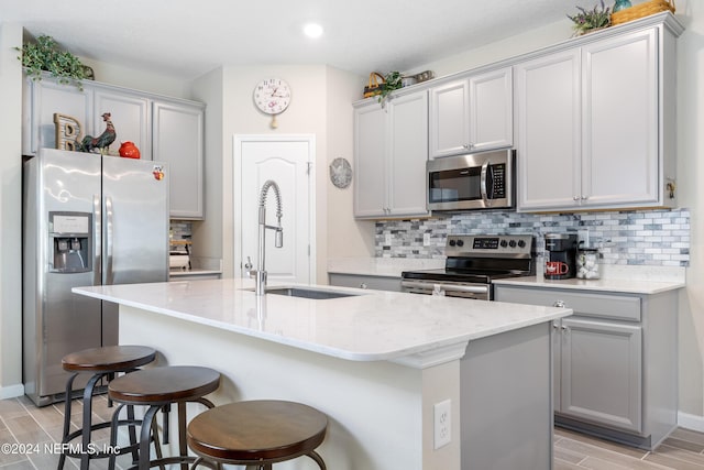 kitchen with stainless steel appliances, light hardwood / wood-style floors, a center island with sink, and sink