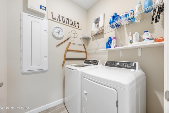 washroom featuring separate washer and dryer, electric panel, and light hardwood / wood-style flooring