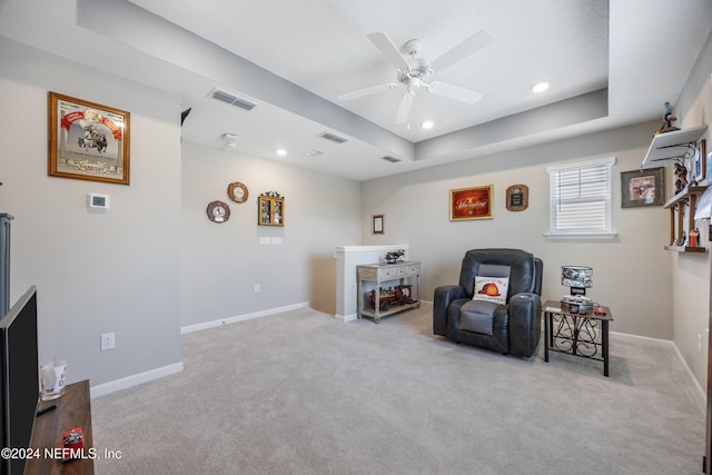 sitting room featuring light colored carpet, ceiling fan, and a tray ceiling