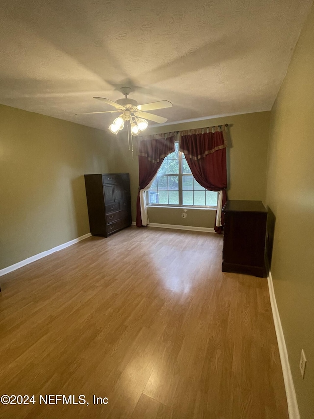 unfurnished room featuring a textured ceiling, hardwood / wood-style flooring, and ceiling fan