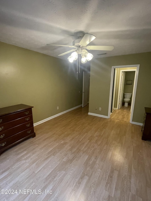 unfurnished bedroom with a textured ceiling, ceiling fan, ensuite bathroom, and light hardwood / wood-style flooring