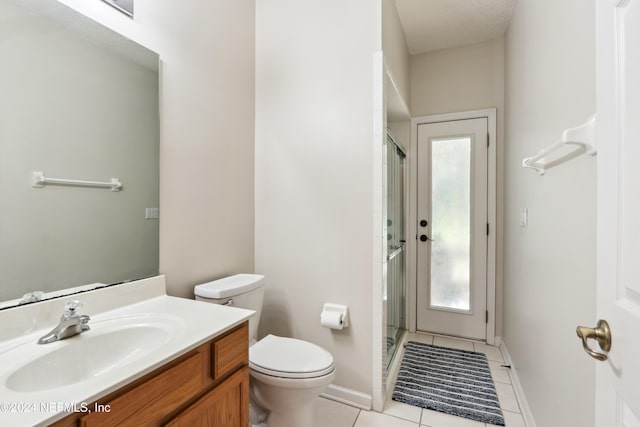 bathroom featuring toilet, vanity, tile patterned floors, and a shower with door