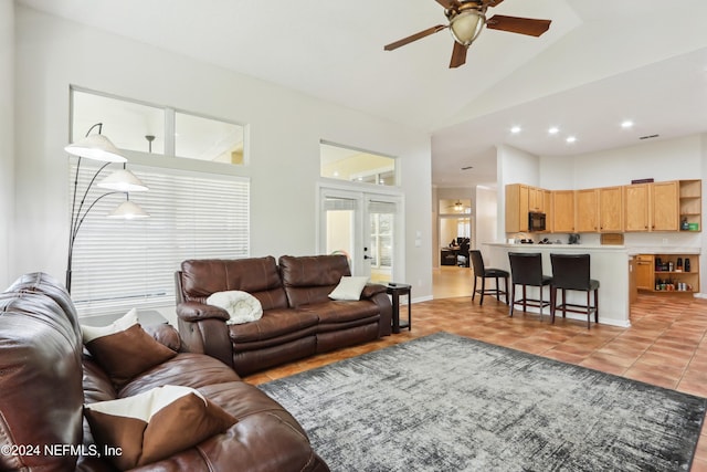 tiled living room featuring ceiling fan, french doors, and vaulted ceiling