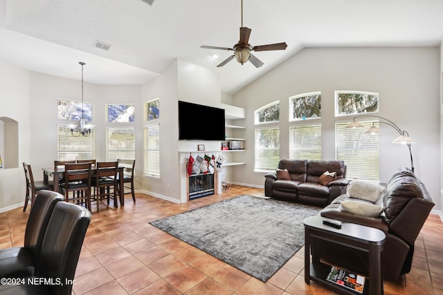 tiled living room featuring high vaulted ceiling and ceiling fan with notable chandelier