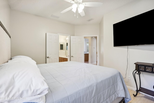 bedroom with ceiling fan, connected bathroom, and light hardwood / wood-style flooring