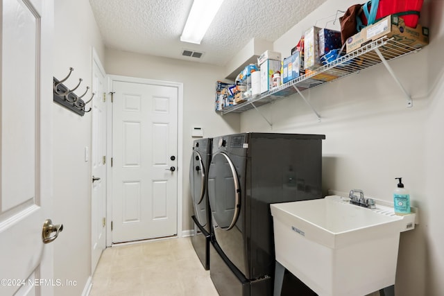 clothes washing area featuring washing machine and clothes dryer, a textured ceiling, and sink