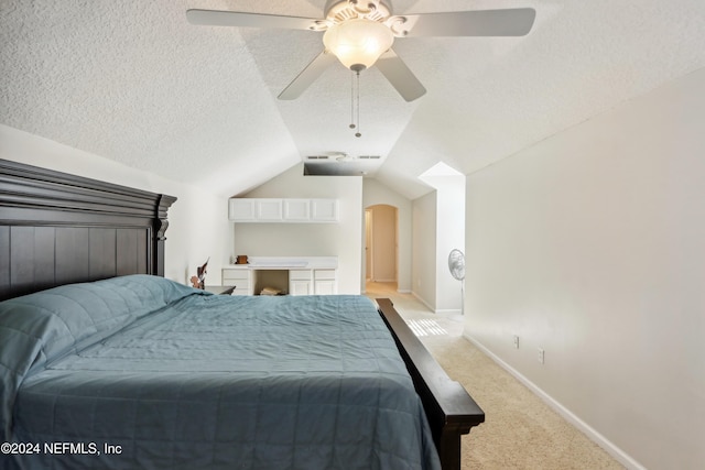 bedroom with light carpet, a textured ceiling, vaulted ceiling, and ceiling fan