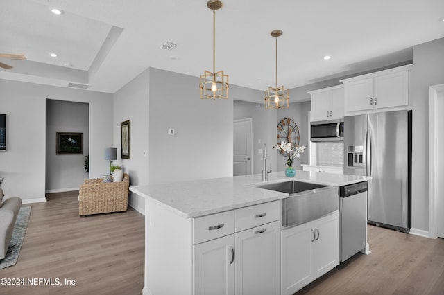 kitchen featuring light wood-type flooring, white cabinetry, stainless steel appliances, and an island with sink