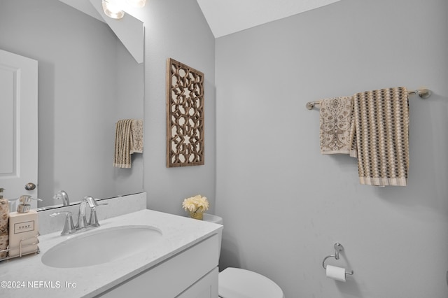 bathroom with vanity, vaulted ceiling, and toilet