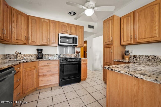 kitchen with appliances with stainless steel finishes, light stone counters, ceiling fan, sink, and light tile patterned floors