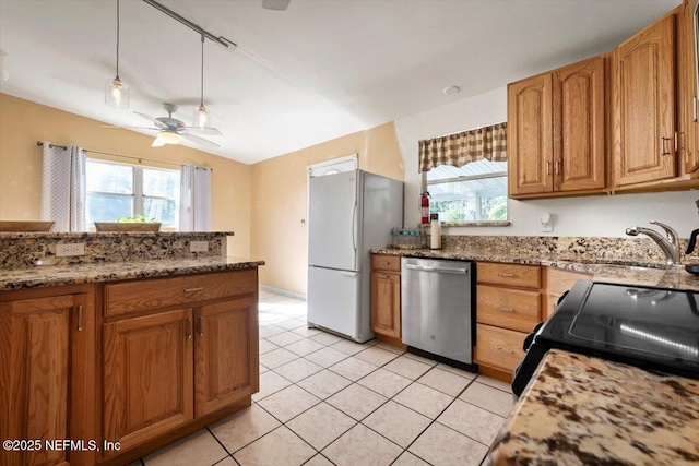 kitchen featuring stainless steel dishwasher, a wealth of natural light, white refrigerator, and stone counters