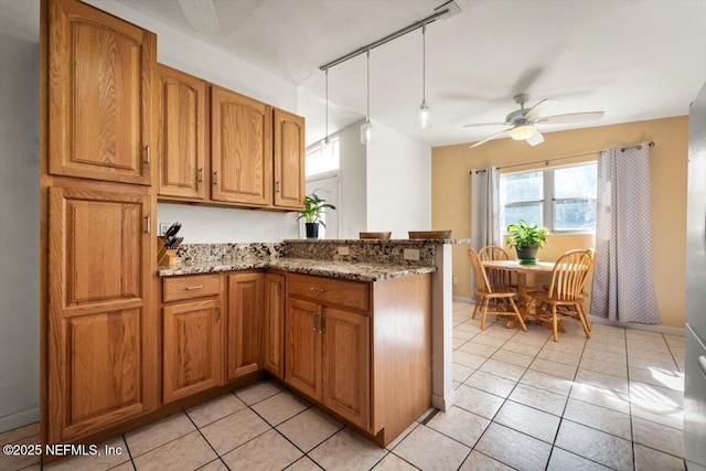 kitchen featuring ceiling fan, light tile patterned flooring, stone countertops, and kitchen peninsula