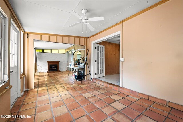 unfurnished sunroom with a fireplace and ceiling fan