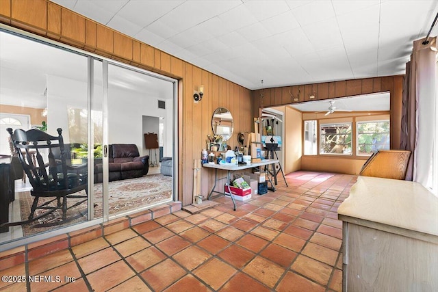 interior space featuring ceiling fan and wood walls