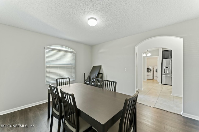 dining room with a textured ceiling, separate washer and dryer, and light hardwood / wood-style flooring