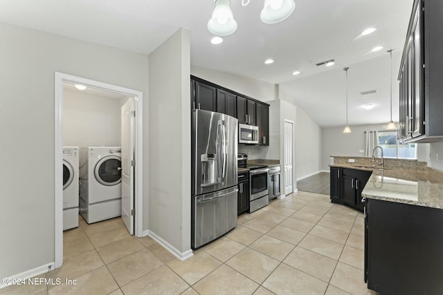 kitchen with pendant lighting, independent washer and dryer, light tile patterned floors, light stone counters, and stainless steel appliances