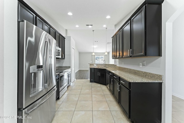 kitchen with sink, hanging light fixtures, light stone countertops, light tile patterned flooring, and stainless steel appliances