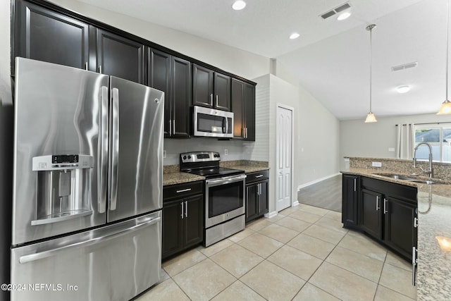 kitchen featuring light stone countertops, sink, stainless steel appliances, decorative light fixtures, and vaulted ceiling