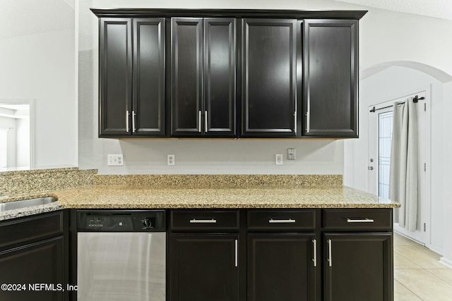 kitchen featuring light stone countertops, vaulted ceiling, sink, light tile patterned floors, and dishwasher