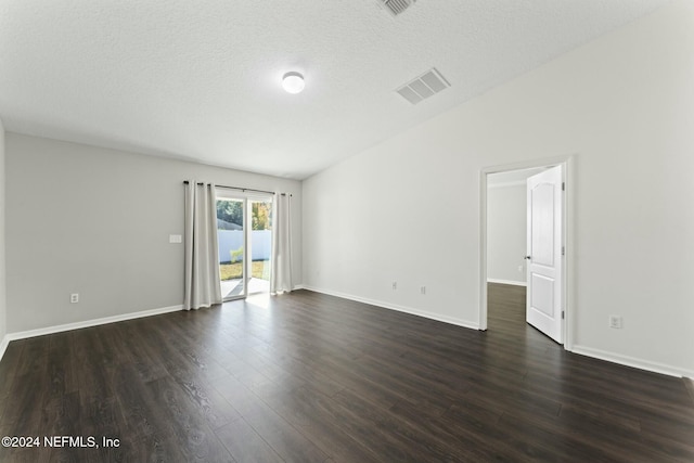 empty room with vaulted ceiling, a textured ceiling, and dark hardwood / wood-style floors