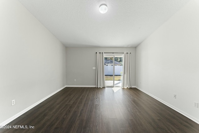 spare room featuring a textured ceiling and dark hardwood / wood-style floors