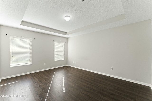 unfurnished room featuring a raised ceiling and dark hardwood / wood-style flooring