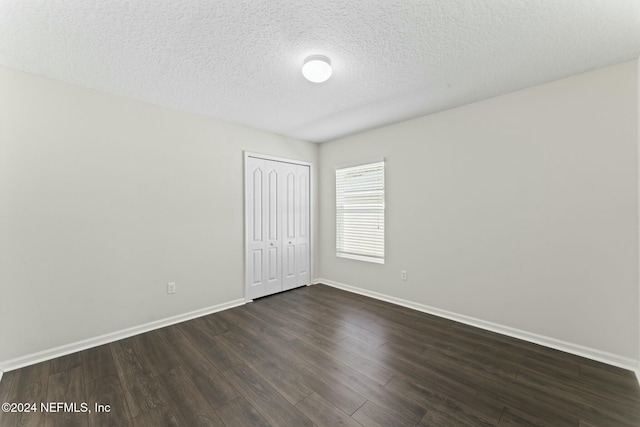 spare room with dark wood-type flooring and a textured ceiling