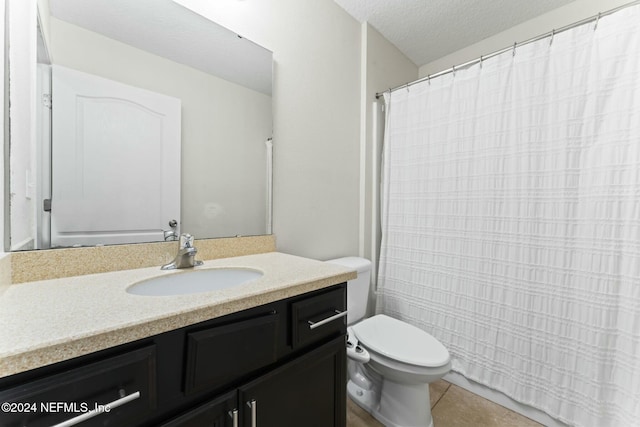 bathroom with tile patterned flooring, vanity, a textured ceiling, and toilet