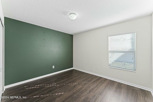 unfurnished room featuring dark hardwood / wood-style flooring and a textured ceiling