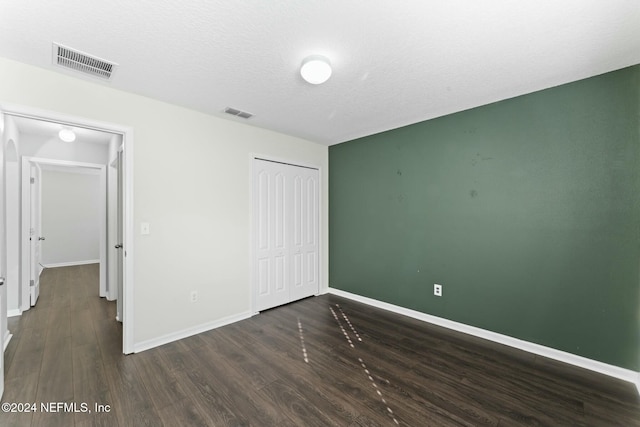 unfurnished bedroom with dark hardwood / wood-style flooring, a textured ceiling, and a closet