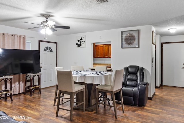 dining space featuring a textured ceiling, ceiling fan, and dark wood-type flooring