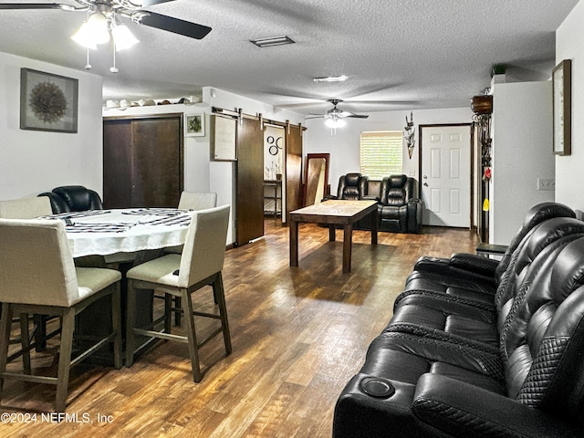 dining space with a textured ceiling, a barn door, and dark hardwood / wood-style floors