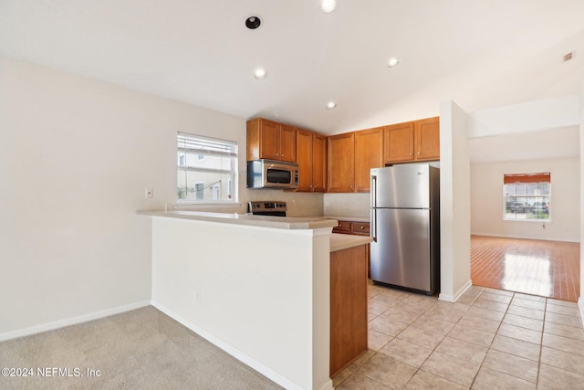 kitchen with backsplash, vaulted ceiling, light tile patterned floors, appliances with stainless steel finishes, and kitchen peninsula