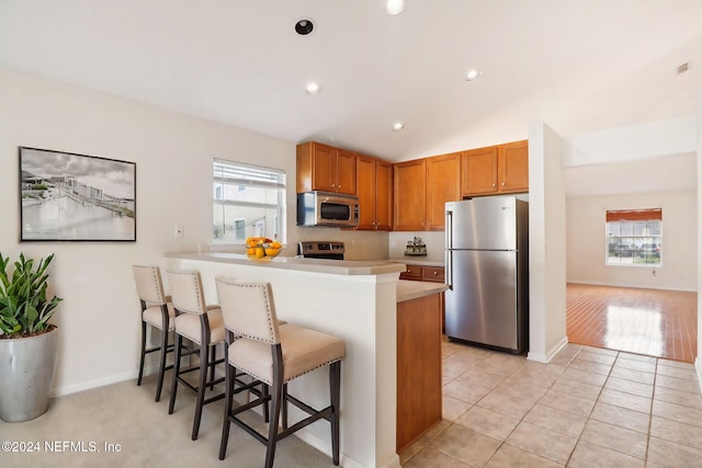 kitchen with kitchen peninsula, stainless steel appliances, plenty of natural light, and light tile patterned flooring