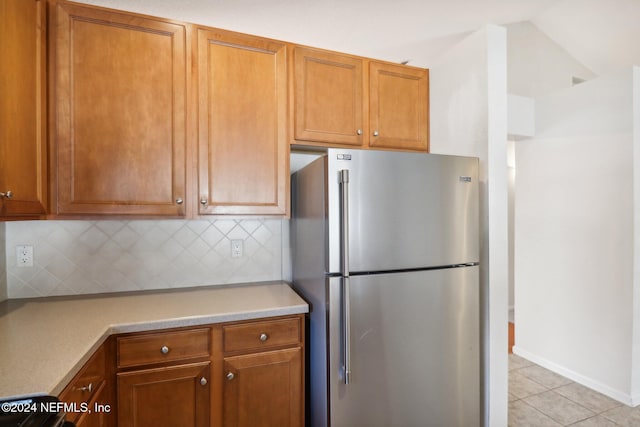 kitchen with backsplash, stainless steel refrigerator, and light tile patterned floors