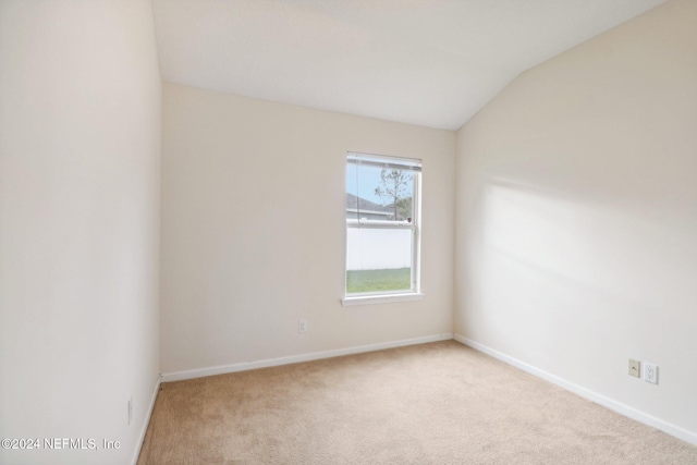 empty room with light colored carpet and vaulted ceiling