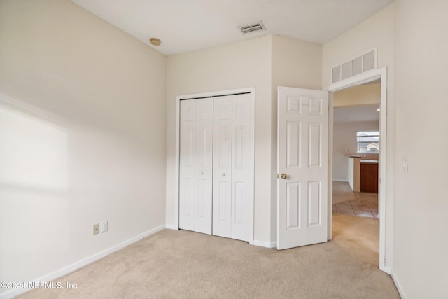 unfurnished bedroom featuring a closet and light colored carpet