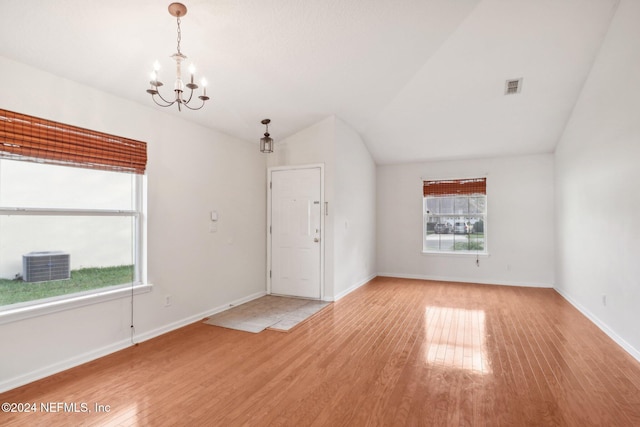 empty room featuring light wood-type flooring, vaulted ceiling, and a notable chandelier