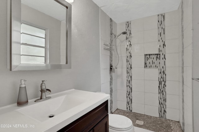 bathroom with vanity, toilet, and tiled shower