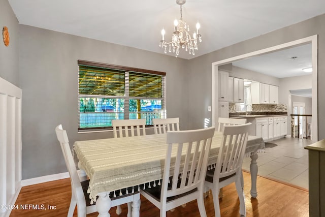 dining area with a chandelier, light wood-type flooring, and sink