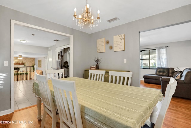 dining room featuring ceiling fan with notable chandelier and light hardwood / wood-style floors