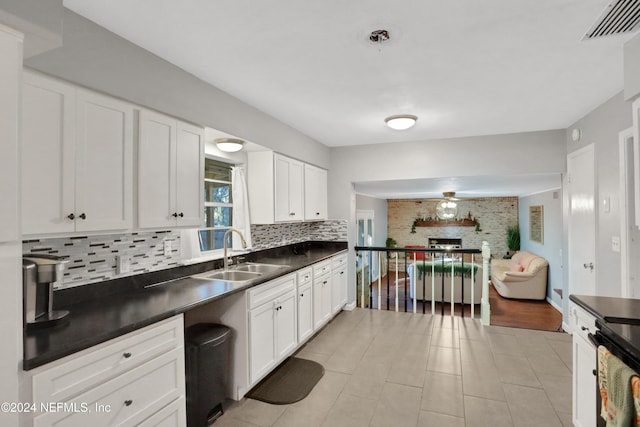 kitchen featuring backsplash, sink, white cabinets, and light tile patterned floors