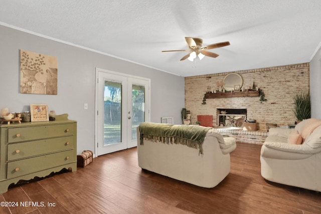 living room with french doors, a brick fireplace, brick wall, ceiling fan, and dark wood-type flooring