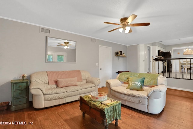 living room with crown molding, ceiling fan with notable chandelier, and hardwood / wood-style flooring