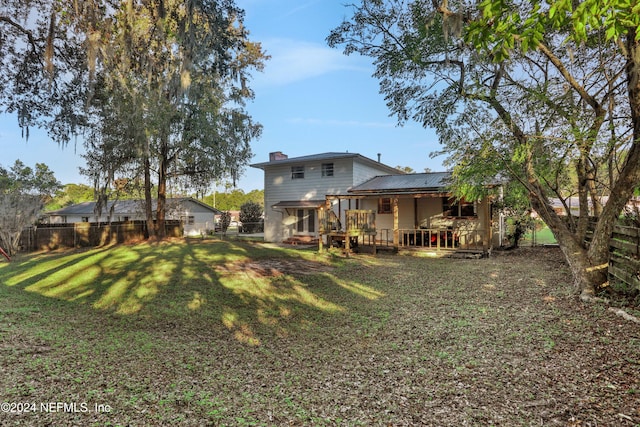 rear view of property featuring a lawn and a wooden deck