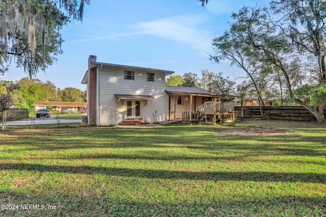 back of house featuring a deck and a lawn