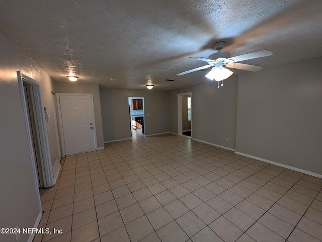 empty room featuring ceiling fan, light tile patterned flooring, and a textured ceiling