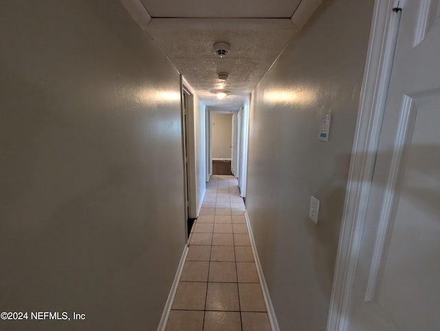 hall with light tile patterned floors and a textured ceiling